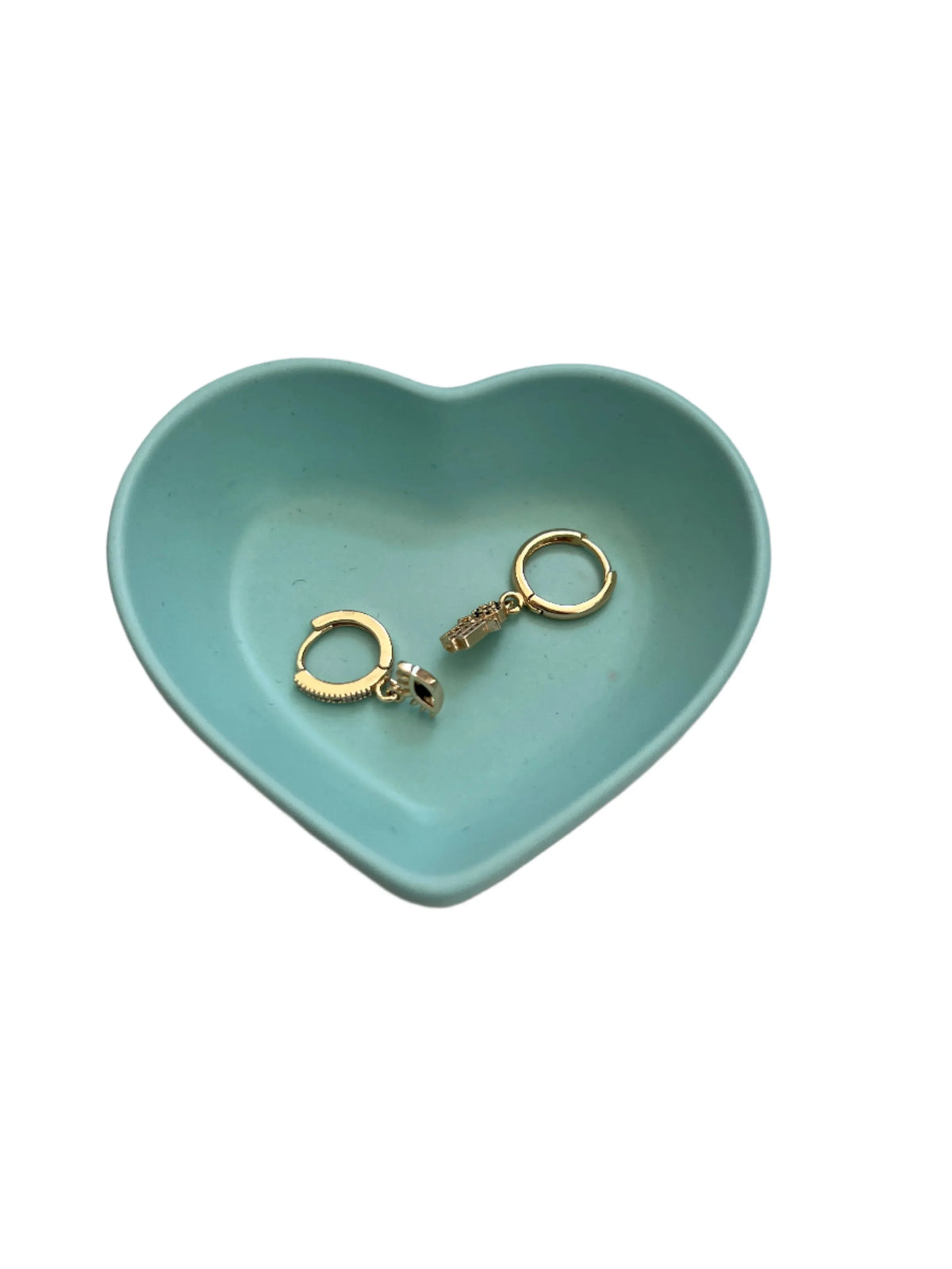 A pair of gold hoop earrings with a small charm, displayed inside a light blue heart-shaped ceramic tray on a white background.